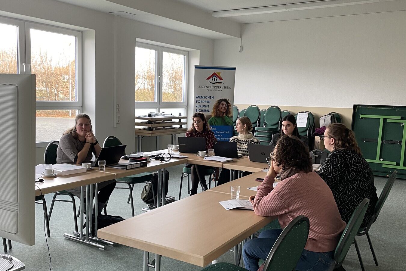 Socios trabajando juntos en mesas en una sala durante una reunión transnacional de proyecto en Schwerin
